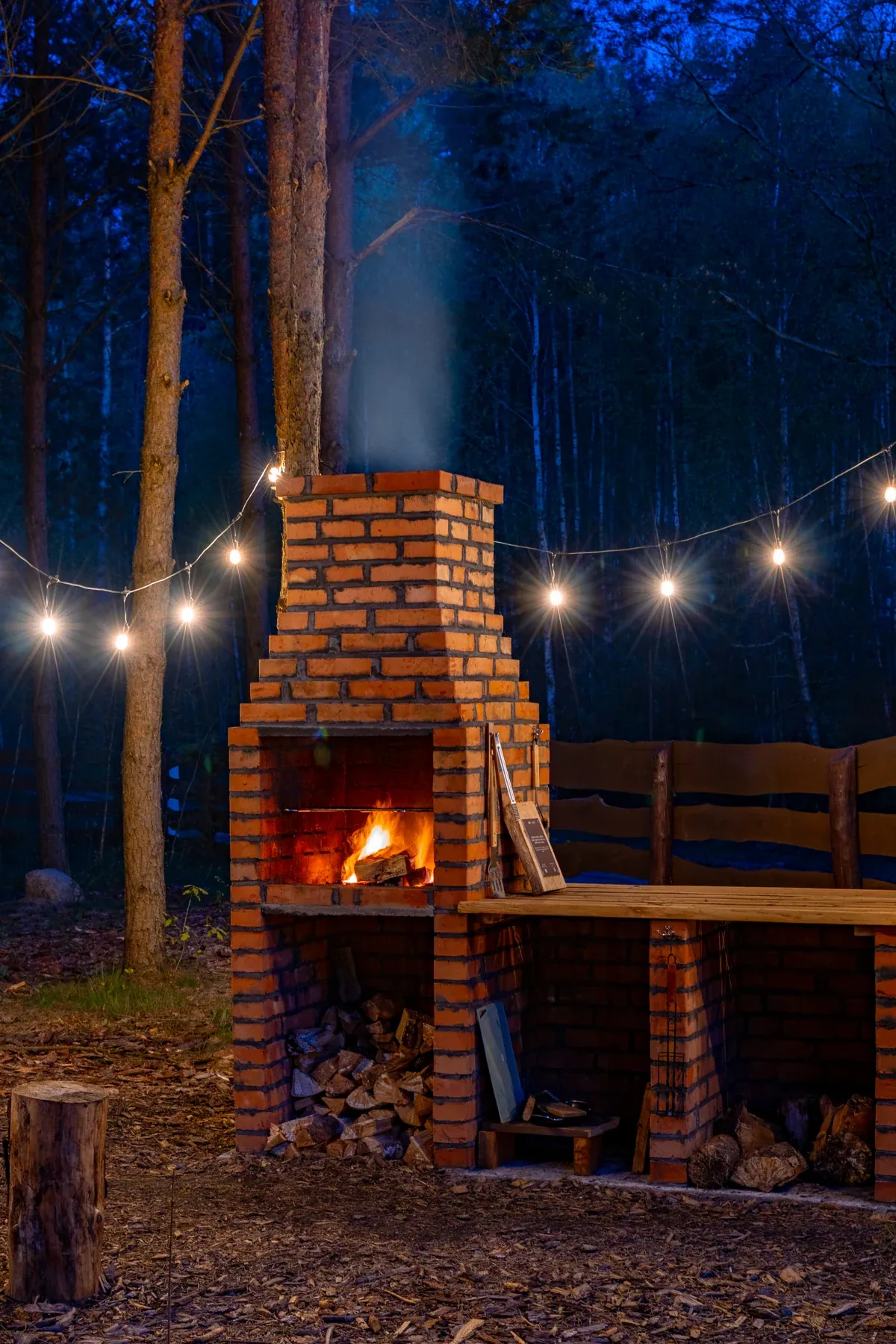 The brick barbecue beneath evening string lights