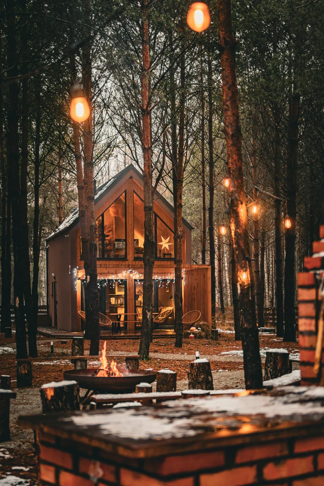 A cabin and fire pit beneath string lights