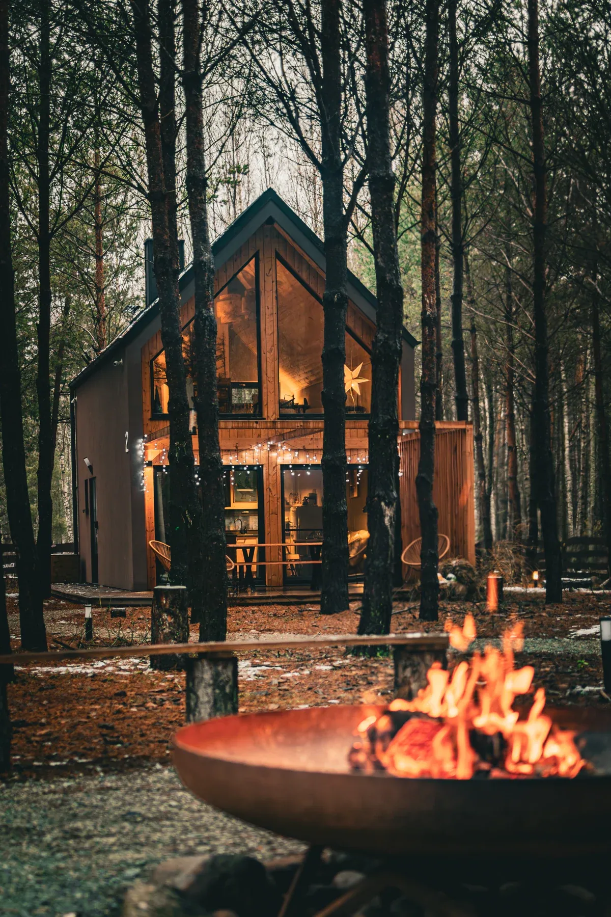 A campfire overlooking an illuminated cabin